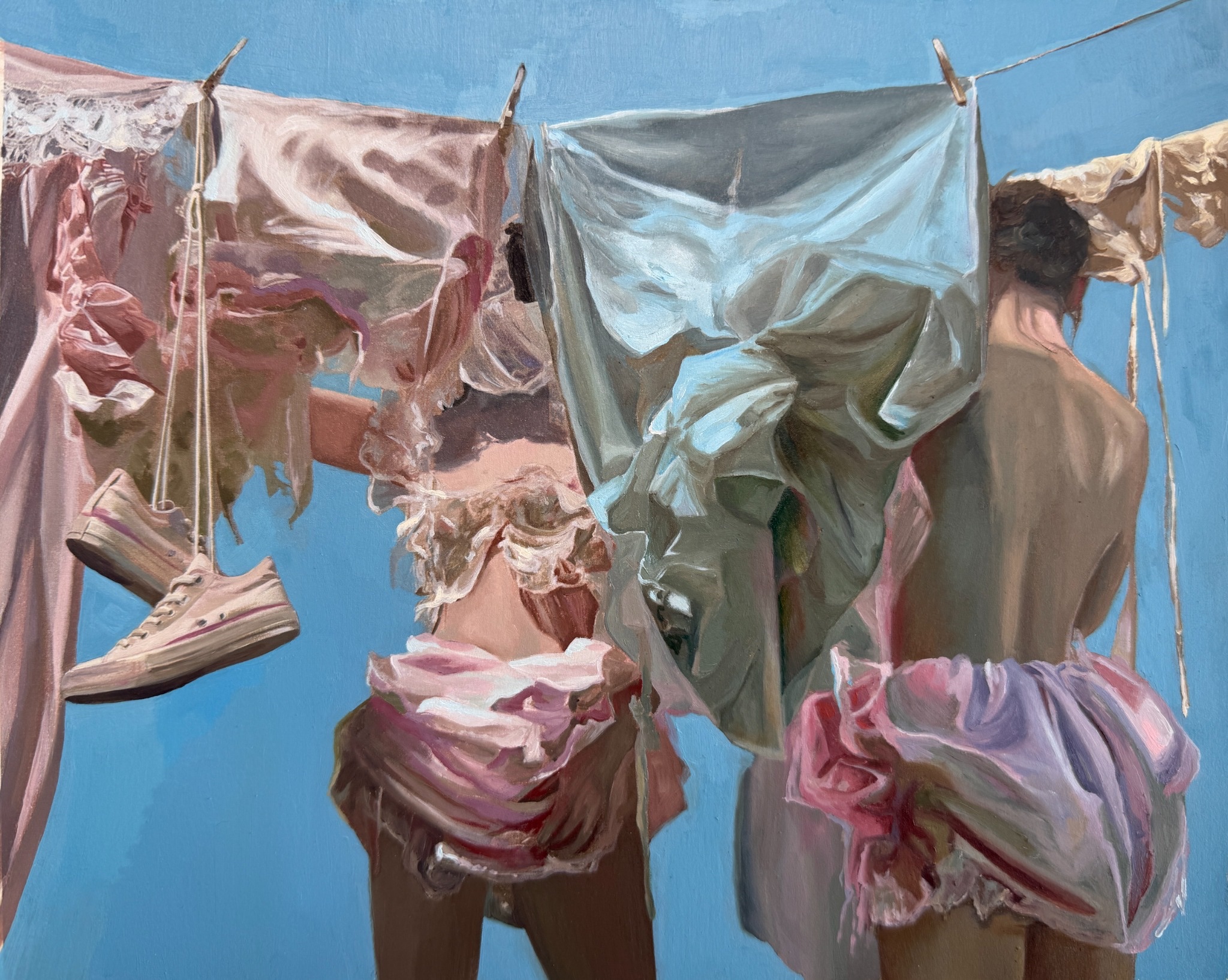 Two figures partially concealed by layered clothing and laundry