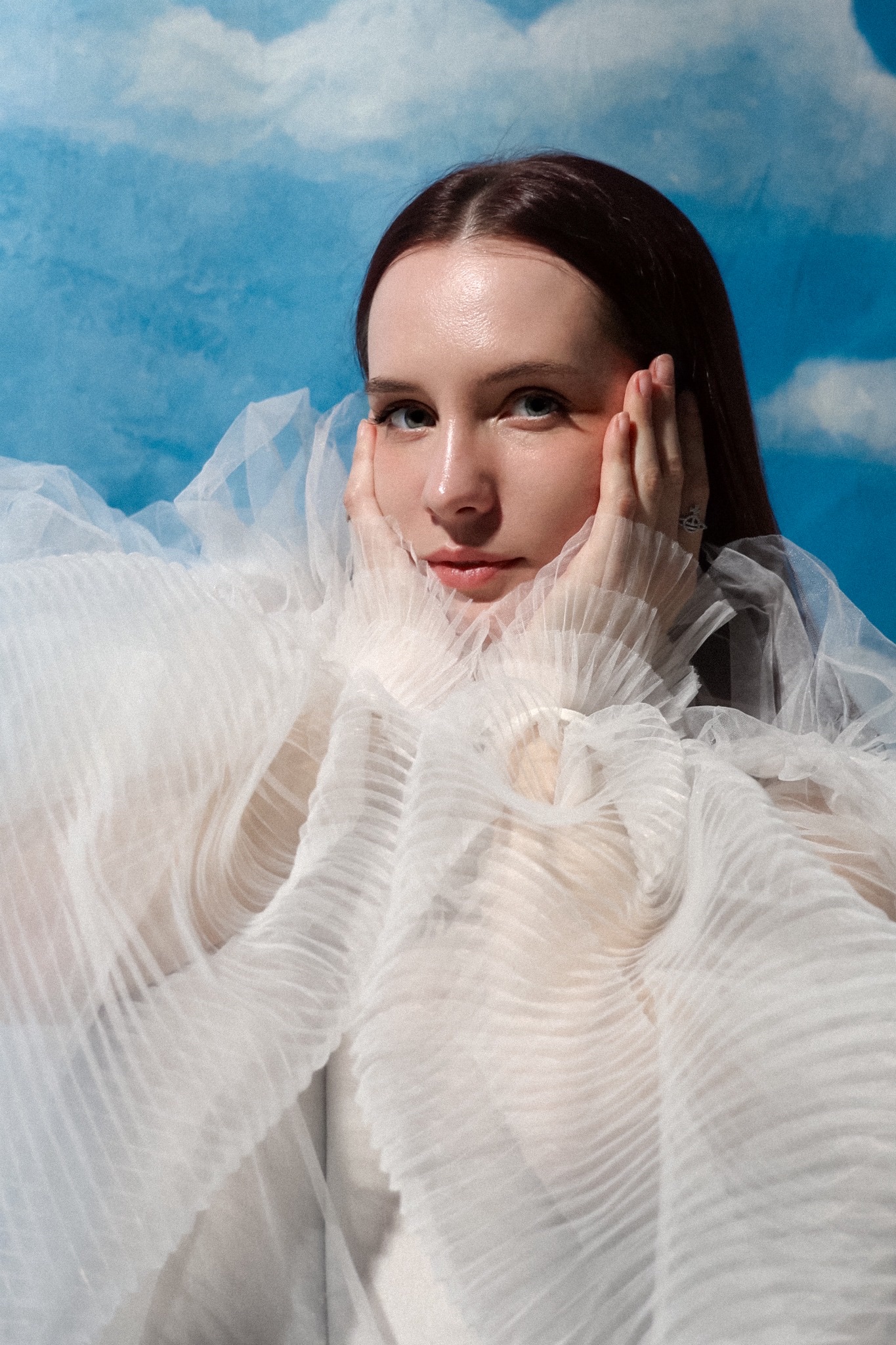 Viktoriia Levina surrounded by layers of white fabric against a blue sky